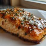 Close-up of a perfectly cooked salmon fillet glazed with honey garlic sauce and sprinkled with herbs.
