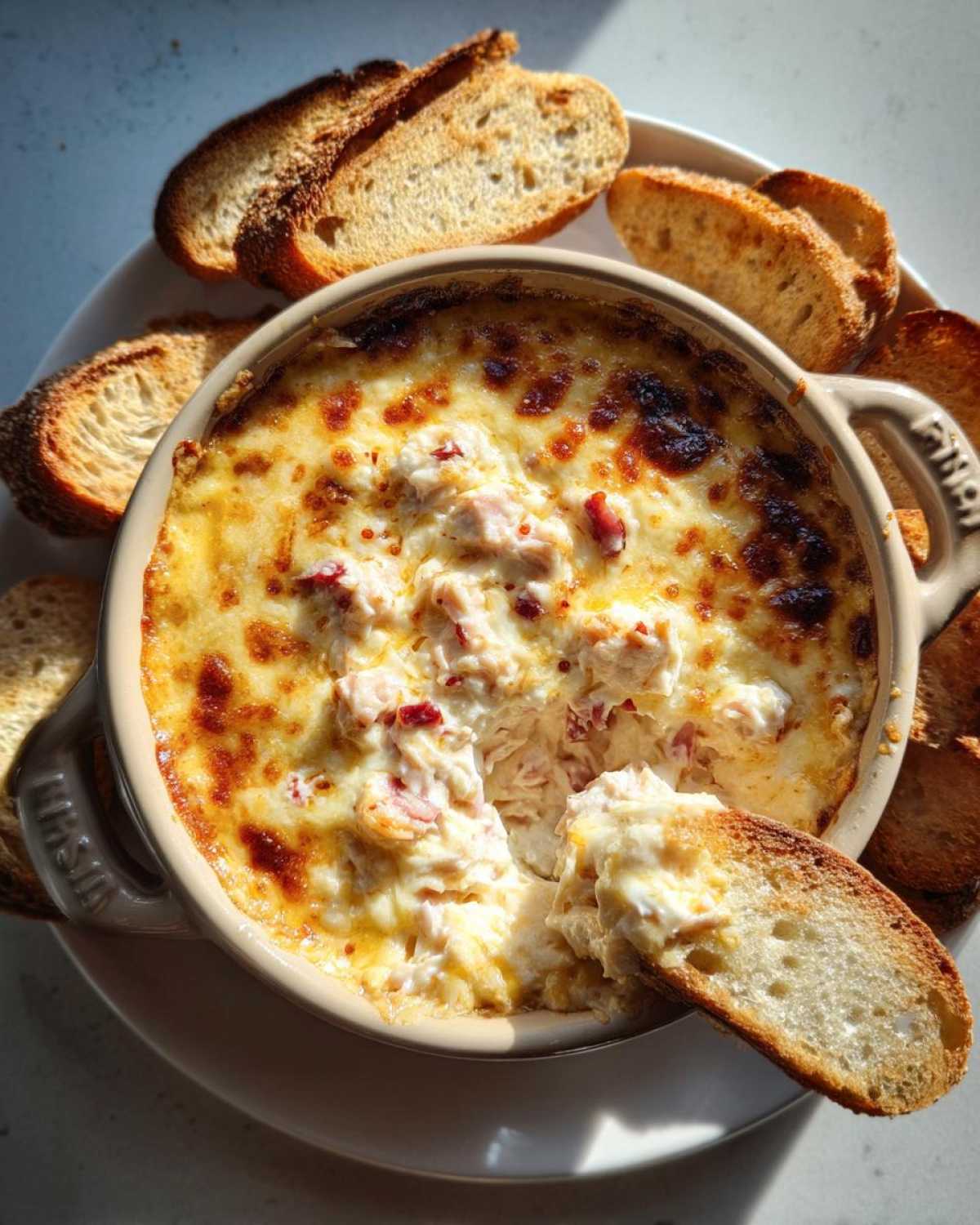 A close-up overhead shot of hot baked reuben dip in a small ceramic dish, surrounded by toasted bread slices.