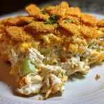 A close-up of a creamy, cheesy serving of hot chicken salad casserole topped with golden brown crackers.