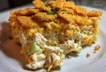 A close-up of a creamy, cheesy serving of hot chicken salad casserole topped with golden brown crackers.