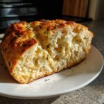 Close-up of a fluffy, cheesy slice of Italian herb and cheese bread showing an airy crumb structure.