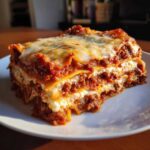 A thick, layered slice of Lasagna with Cottage Cheese showing meat sauce, pasta, and creamy white filling.