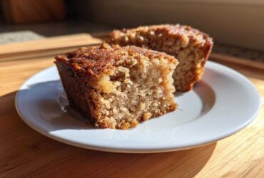 Two moist squares of homemade applesauce cake sitting on a small white plate, highlighted by sunlight.