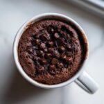 Overhead view of a rich, moist chocolate chip mug cake topped with melted chocolate chips.