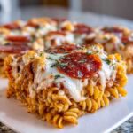 Close-up of a square slice of baked pizza pasta topped with melted mozzarella, pepperoni, and herbs.