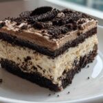 A layered slice of Oreo dirt cake featuring chocolate cake, creamy filling, and crushed cookies on top.