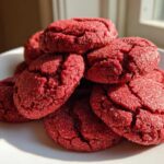 A stack of vibrant, crinkly red velvet cake mix cookies dusted with sugar on a white plate.