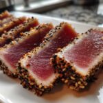 Close-up of perfectly Seared Ahi Tuna slices, crusted with sesame seeds, showing a rare, deep red center.