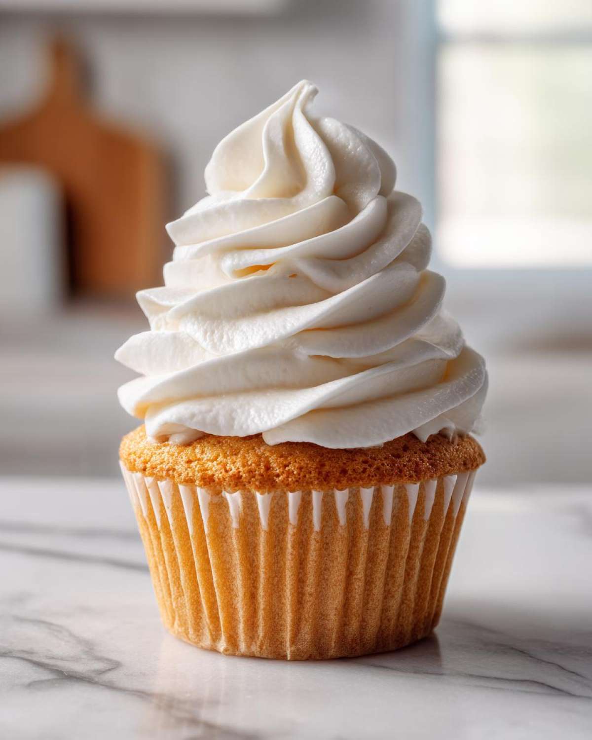 A single, perfectly baked vanilla cupcake topped with a tall swirl of white vanilla buttercream frosting.