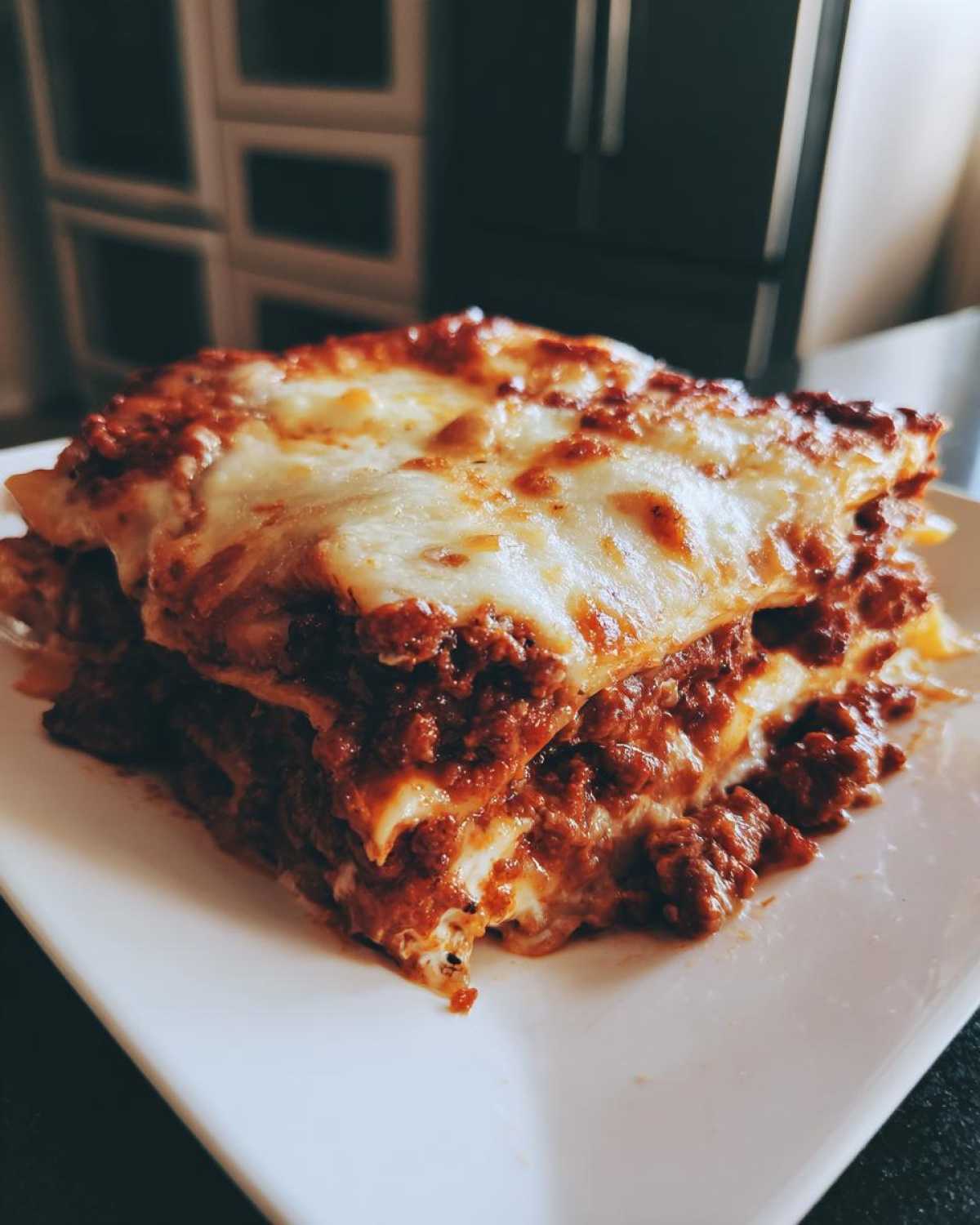 A tempting, layered slice of homemade lasagna featuring rich meat sauce and melted, bubbly cheese topping.