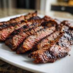 Close-up of perfectly grilled and sliced steak, showing a medium-rare center, prepared with carne asada marinade.