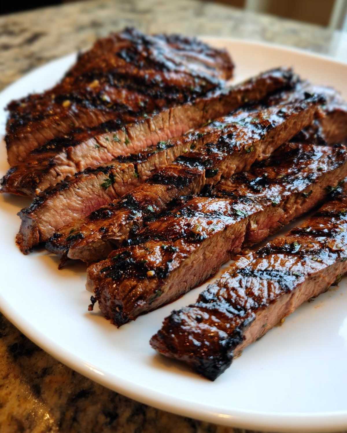 Close-up of medium-rare steak slices showing grill marks, coated in a glossy Carne asada marinade.