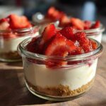 Close-up of a single serving Protein Cheesecake in a glass jar topped with fresh, sliced strawberries.
