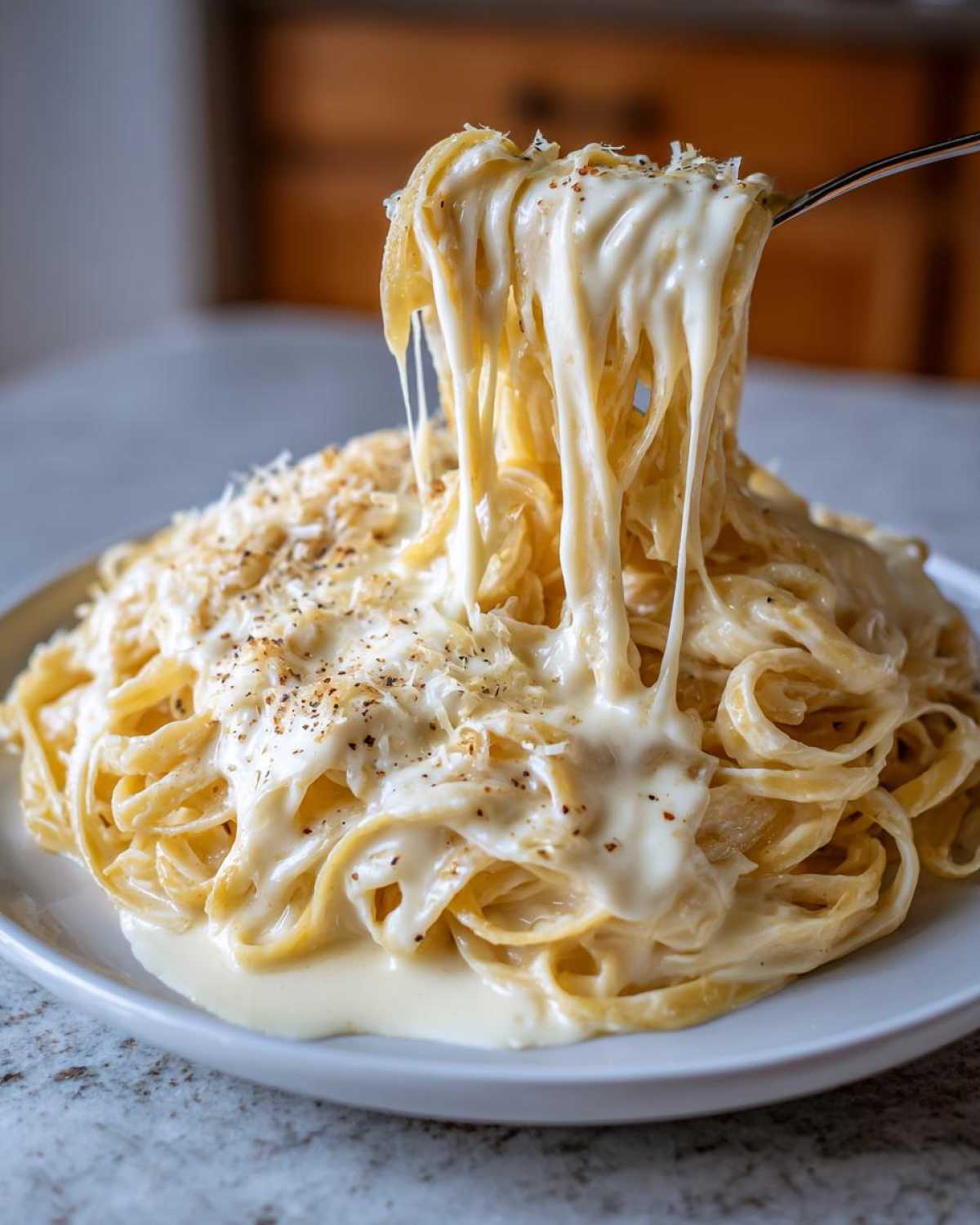 A fork lifts a massive, cheesy, and creamy portion of fettuccine coated in rich olive garden alfredo sauce.