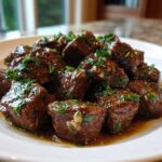 Close-up of tender crockpot steak bites coated in a rich sauce and topped with fresh chopped parsley.