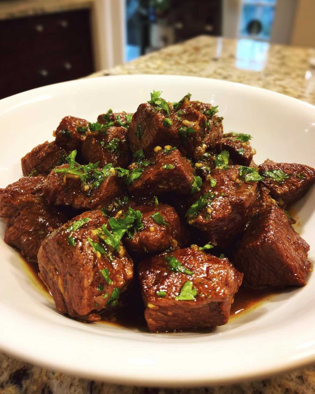 Close-up of tender, saucy crockpot steak cubes garnished with fresh chopped parsley.