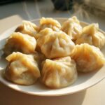 A plate of freshly steamed Traditional Chinese Dumplings, glistening and emitting steam in warm sunlight.