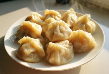 A plate of freshly steamed Traditional Chinese Dumplings, glistening and emitting steam in warm sunlight.