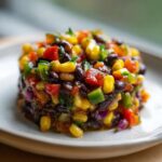 A molded serving of colorful cowboy caviar featuring black beans, corn, red peppers, and green peppers.