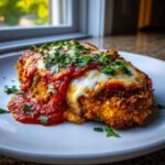 A close-up of crispy Air Fryer Chicken Parmesan topped with melted mozzarella and marinara sauce, garnished with parsley.