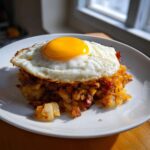 A serving of Air Fryer Corned Beef Hash with crispy potatoes topped with a perfectly fried sunny-side-up egg.
