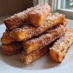 A close-up stack of golden brown Air Fryer French Toast Sticks heavily coated in sparkling cinnamon sugar.
