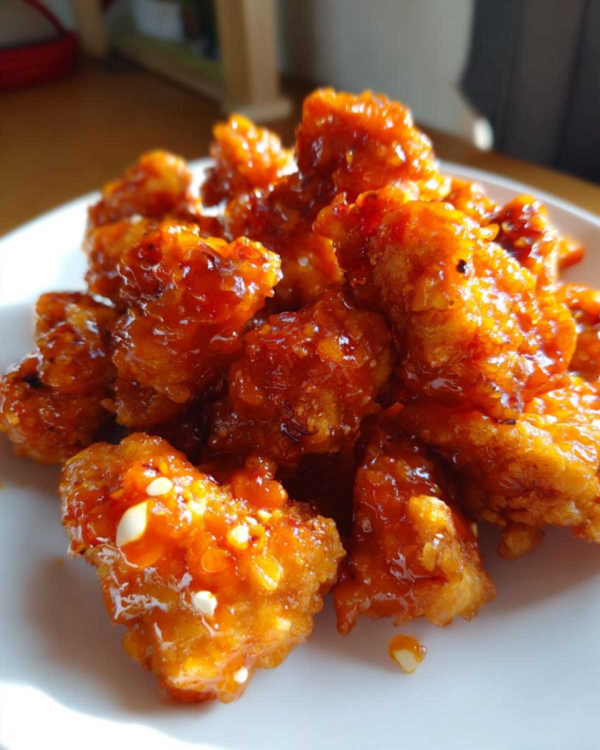 Close-up of crispy, glazed pieces of Air Fryer Orange Chicken piled on a white plate.