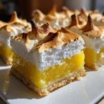 A close-up of perfectly cut Lemon Meringue Pie Bars showing the crust, bright yellow curd, and toasted meringue peaks.
