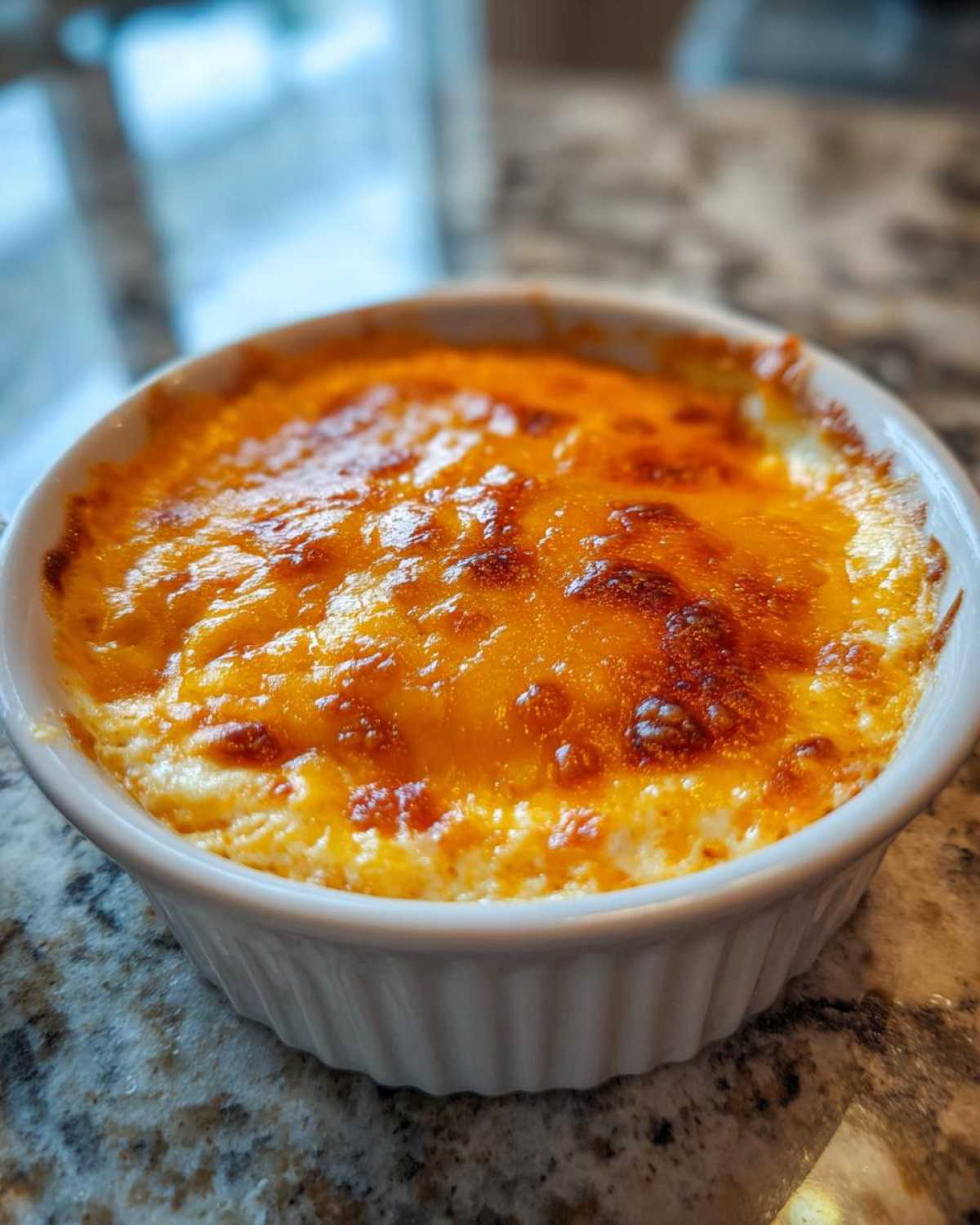Close-up of hot, bubbly Baked Buffalo Chicken Dip with a perfectly melted and browned cheese topping in a white ramekin.