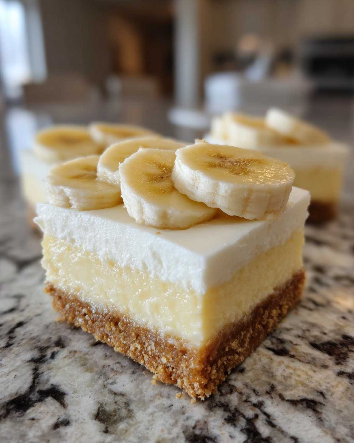 A close-up of a layered Banana Pudding Cheesecake Bars slice topped with fresh banana slices.