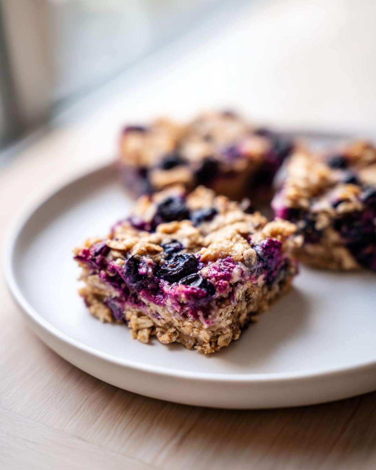 A close-up of a square piece of Blueberry Baked Oatmeal Squares showing oats and vibrant purple blueberries.