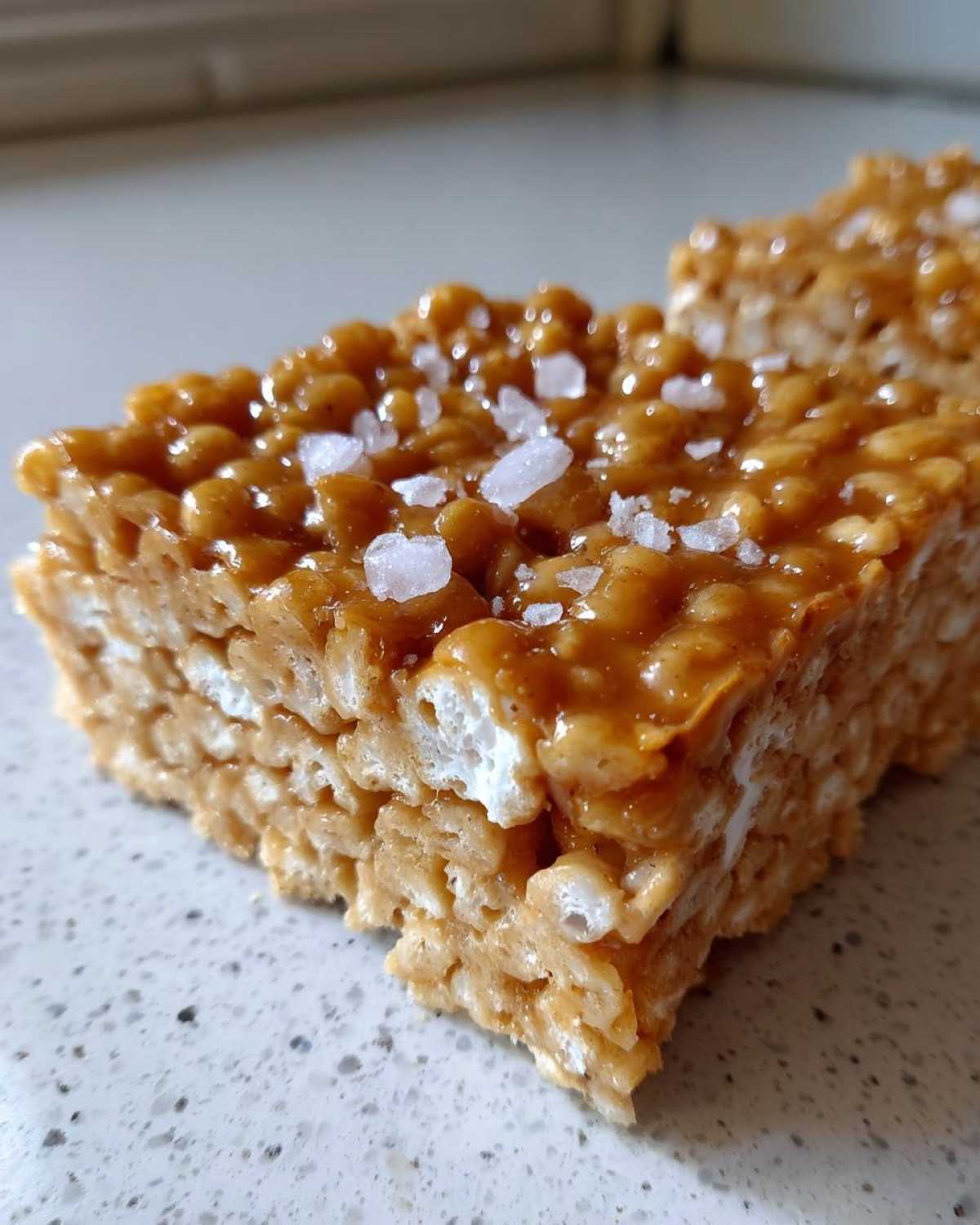 Close-up view of a thick Brown Butter Rice Krispie Treat Bar topped with flaky sea salt.