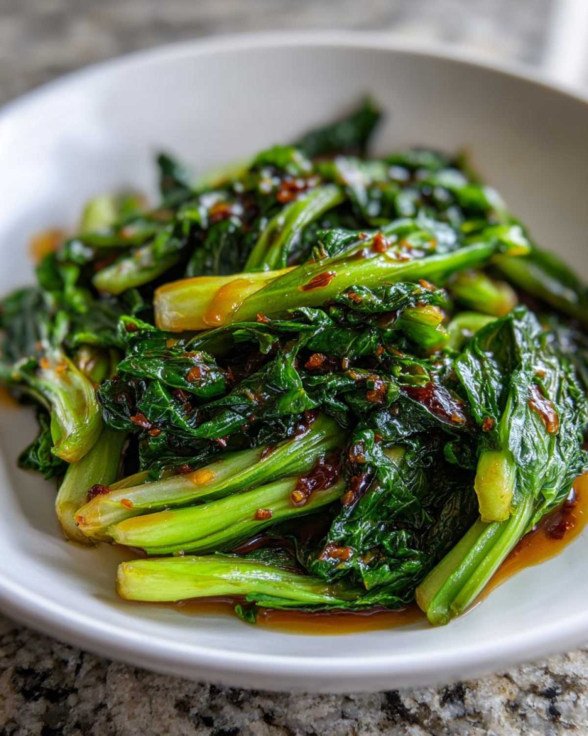 Close-up of vibrant green, glossy Cabbage Stir Fry with Garlic Ginger Sauce coating the leaves and stems.