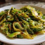 Close-up of vibrant green Cabbage Stir Fry with Garlic Ginger Sauce served on a white plate.