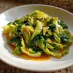 A close-up of vibrant Cabbage Stir Fry with Garlic Ginger Sauce served on a white plate.