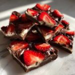 A stack of rich Chocolate Covered Strawberry Bark pieces featuring dark chocolate, white filling, and fresh strawberry slices.