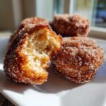 Close-up of a Cinnamon Sugar Air Fryer Donut broken in half showing the fluffy interior coated in sugar.