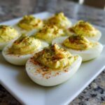 Close-up of several Classic Deviled Eggs with Dill Pickle Relish, topped with paprika and fresh dill.