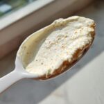 A spoonful of creamy, white Copycat Taco Bell Chicken Quesadilla Sauce speckled with black pepper and orange spices.