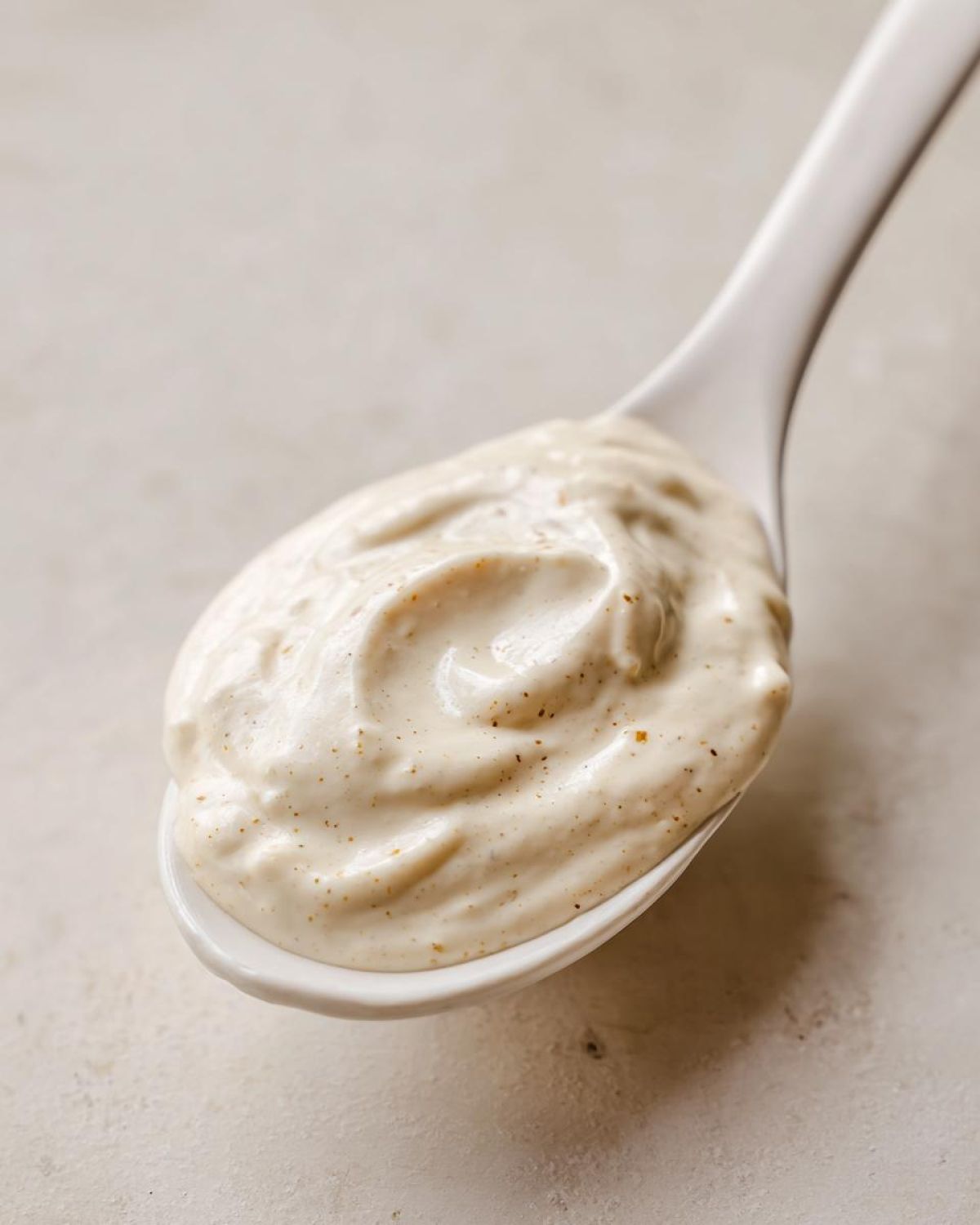 Close-up of thick, creamy Copycat Taco Bell Chicken Quesadilla Sauce swirled on a white spoon.
