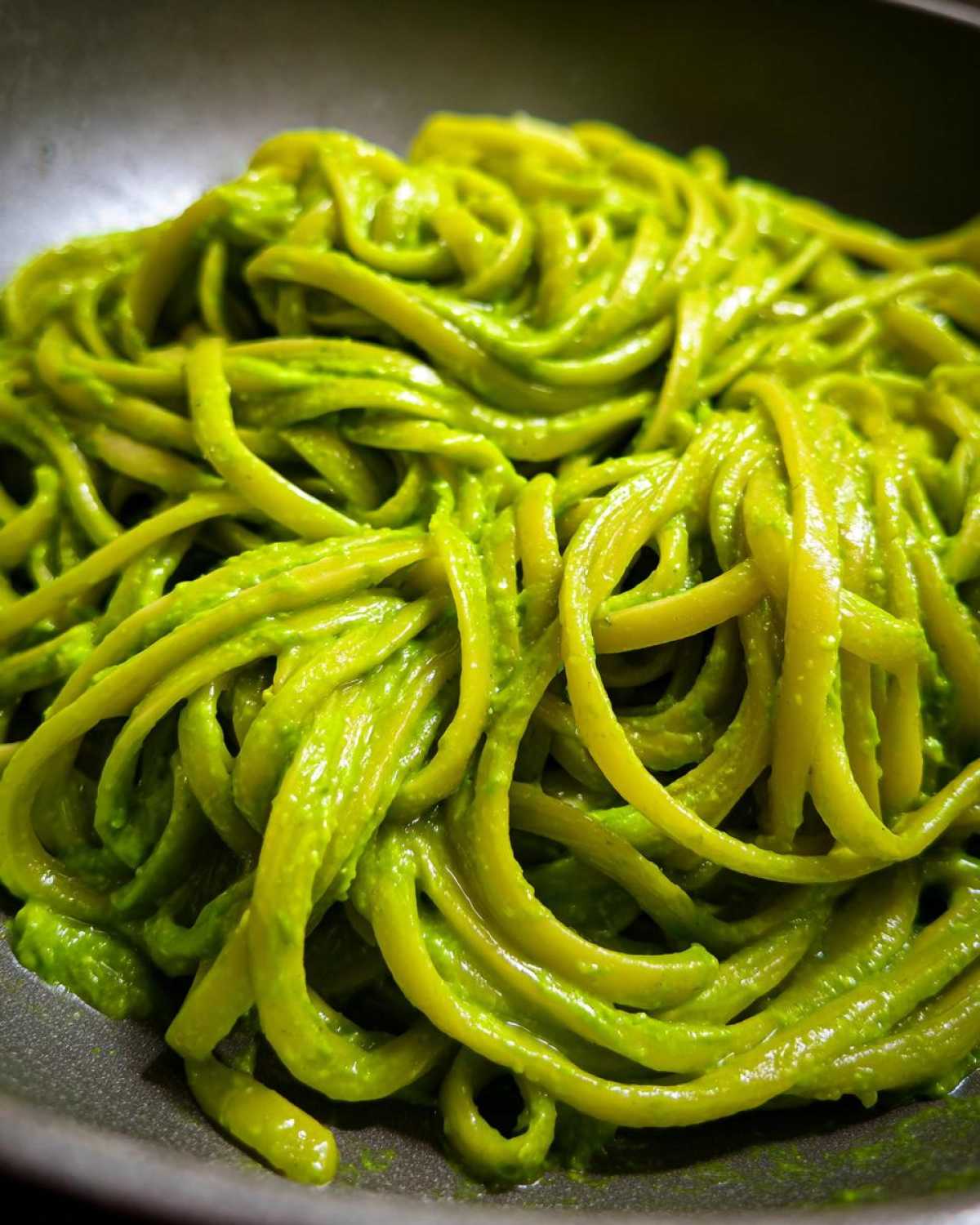 Close-up of bright green, saucy Creamy Avocado Pasta tossed with linguine or fettuccine noodles.