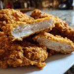 Close-up of Crispy Baked Chicken Tenders with Cornflake Crust, showing the moist white interior.