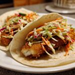 Two Crispy Baked Fish Tacos filled with breaded fish and topped generously with colorful lime slaw.