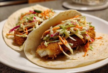Two Crispy Baked Fish Tacos filled with breaded fish and topped generously with colorful lime slaw.
