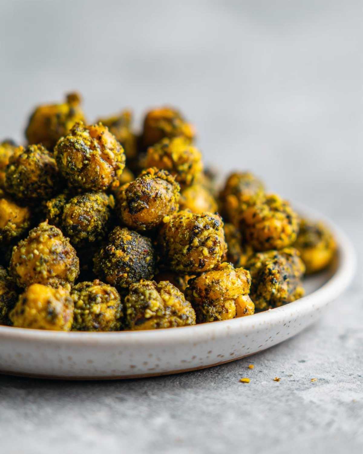 A close-up of a small bowl filled with Crunchy Air Fryer Ranch Chickpeas, seasoned with yellow and green spices.
