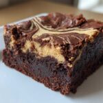 Close-up of a fudgy Dark Chocolate Tahini Brownie square with a creamy tahini swirl on top.