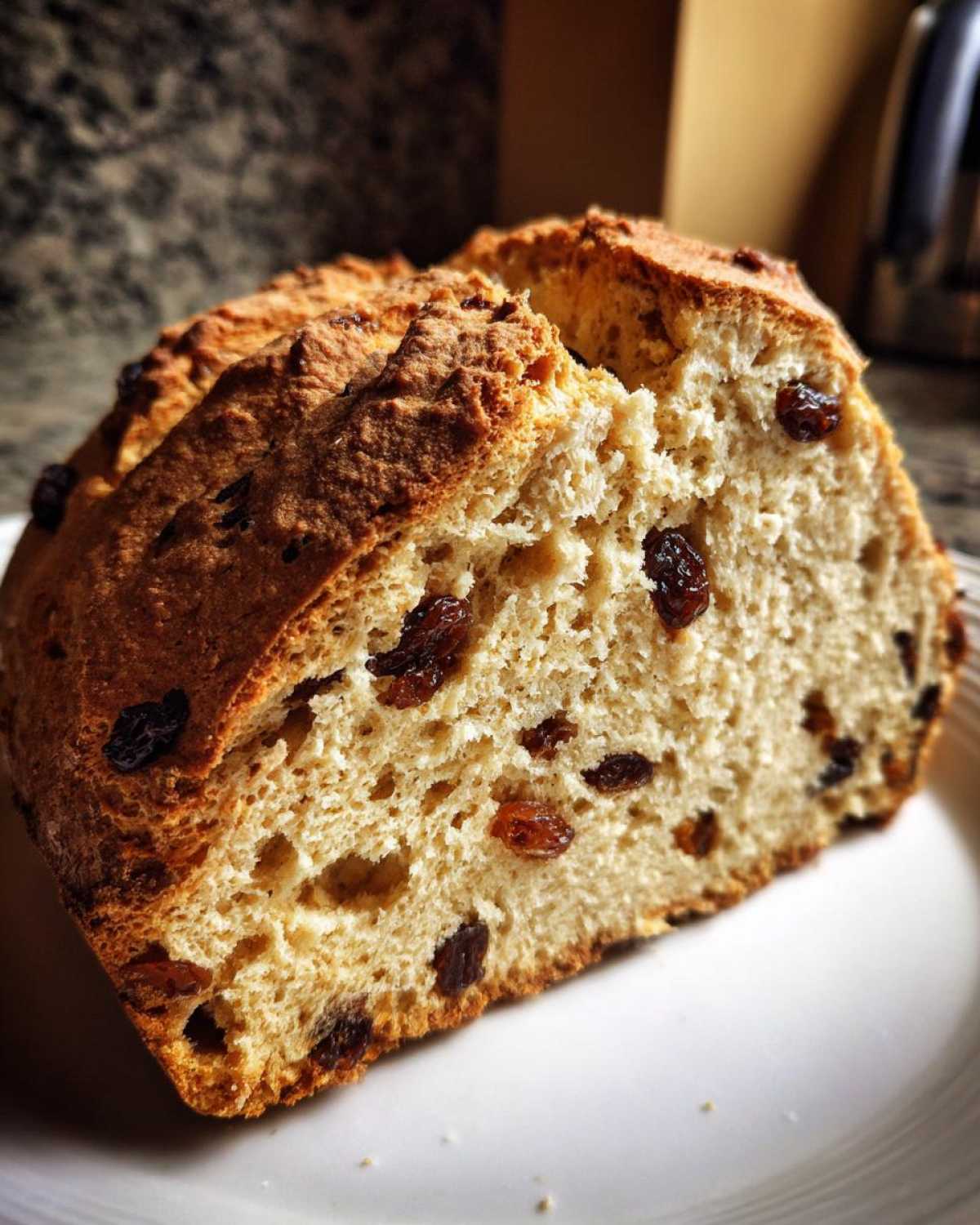 Close-up of a thick slice of Easy Irish Soda Bread with Buttermilk and Raisins showing a golden crust and soft interior.