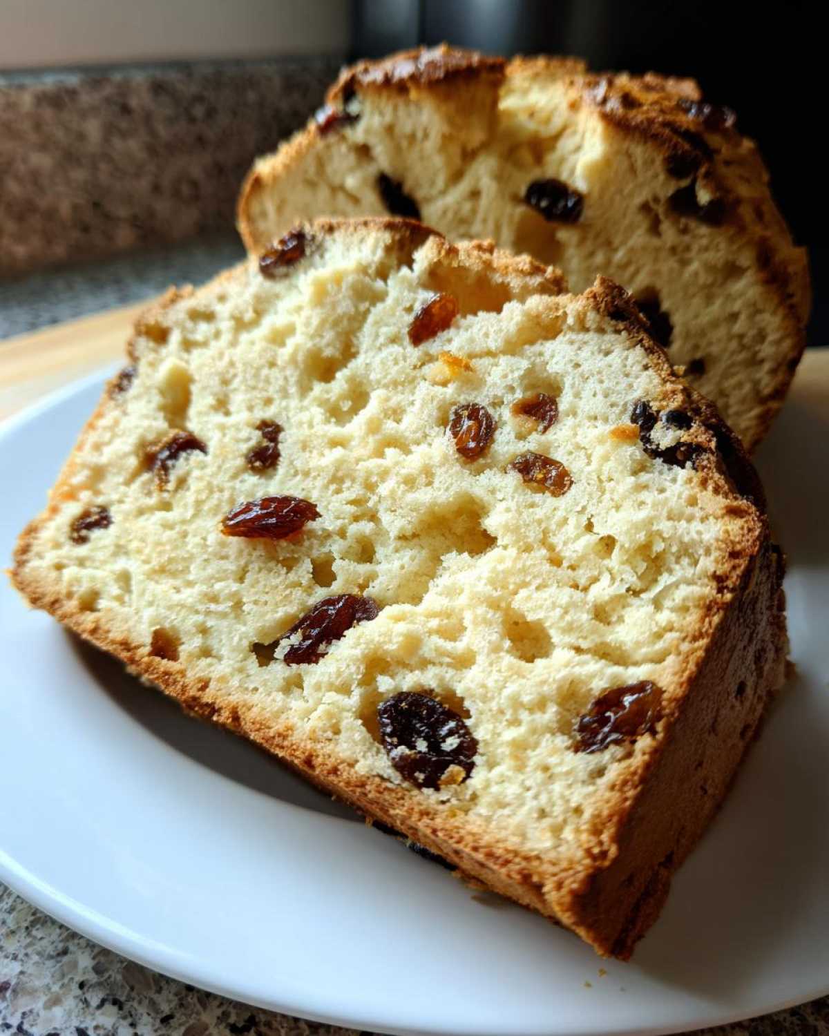 Close-up of a thick slice of Easy Irish Soda Bread with Buttermilk and Raisins showing the soft crumb and dark raisins.