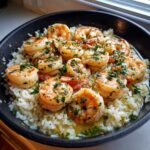 Close-up of cooked shrimp nestled in rice, coated in garlic butter sauce and fresh parsley, ready for the Garlic Butter Shrimp and Rice Skillet.