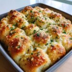 Close-up of freshly baked Garlic Parmesan Pull-Apart Bread rolls topped with melted cheese and fresh parsley.